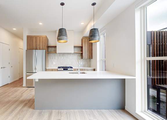 A modern kitchen with a white island and lights at One West Drive Apartments, Excelsior, MN