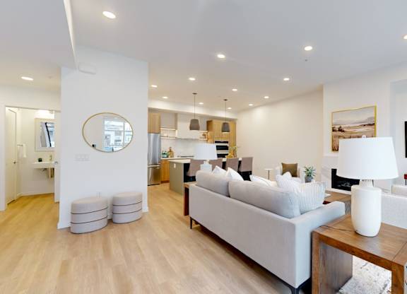 A modern living room with a white sofa set and a wooden coffee table.