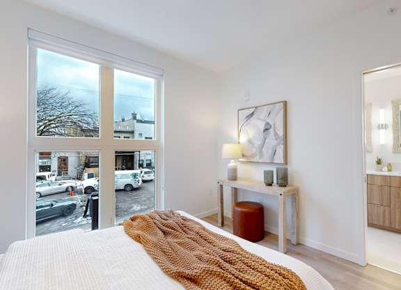 A bedroom with a large bed and a view of the street outside.