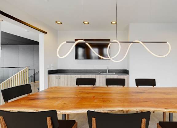 A modern dining room with a wooden table and black chairs.