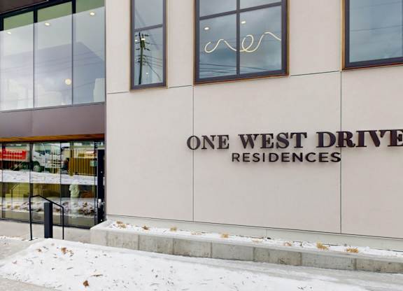 A building with a glass facade and a sign that reads "One West Drive Residences.".