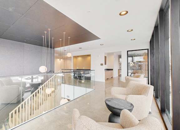 A modern living room with a glass table and white chairs.