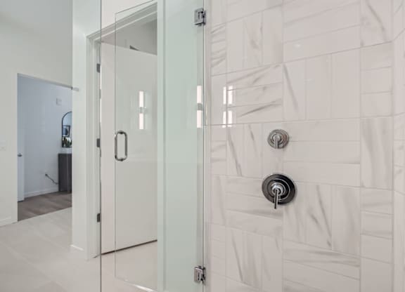 a white bathroom with a glass shower door at One West Drive Apartments, Excelsior, 55331