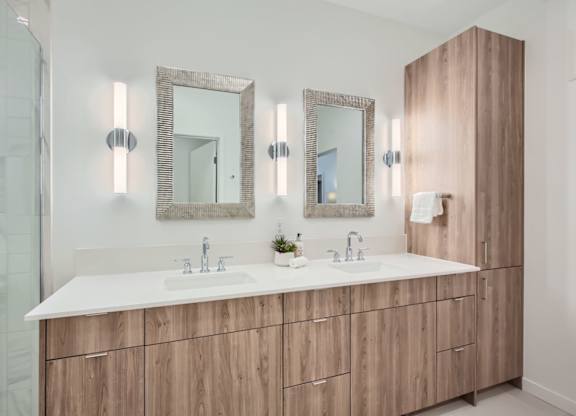 a bathroom with two sinks and two mirrors at One West Drive Apartments, Minnesota