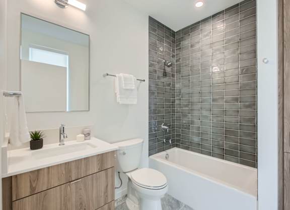a bathroom with a toilet and a tub and a sink at One West Drive Apartments, Excelsior, MN