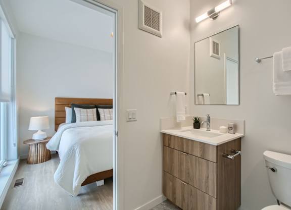 a bedroom with a bed and a bathroom with a toilet and a sink at One West Drive Apartments, Excelsior