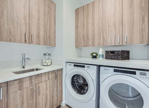 a washer and dryer in a laundry room with wooden cabinets at One West Drive Apartments, Excelsior