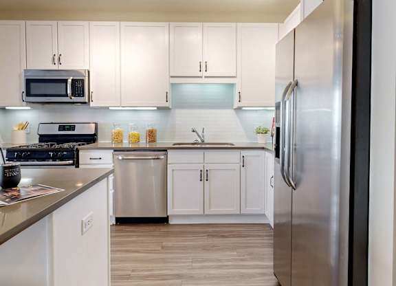 A modern kitchen with white cabinets and stainless steel appliances.