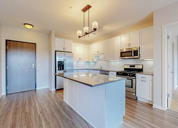A kitchen with white cabinets and a wooden floor.