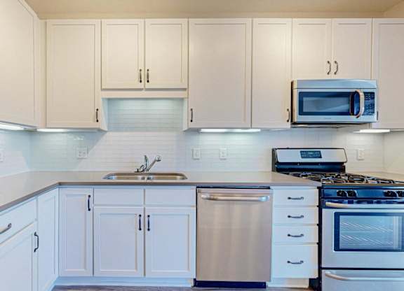 A kitchen with white cabinets and appliances.