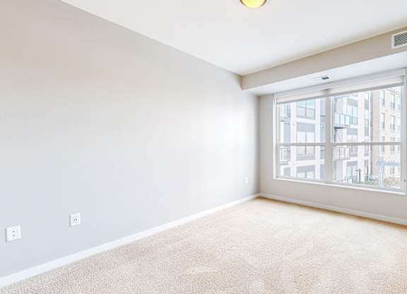 A room with a large window and a carpeted floor.
