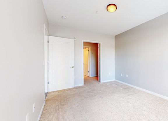 A room with a white door and a carpeted floor.