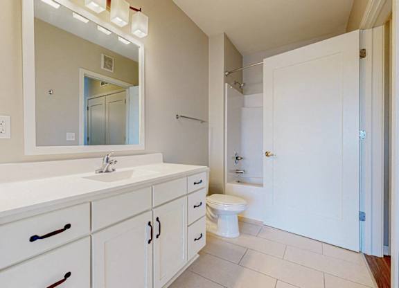 A white bathroom with a sink, toilet, and mirror.