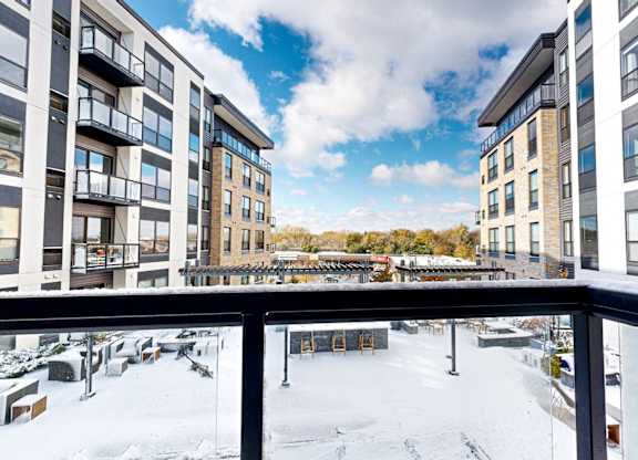 A view from a balcony of a snow-covered courtyard between two buildings.
