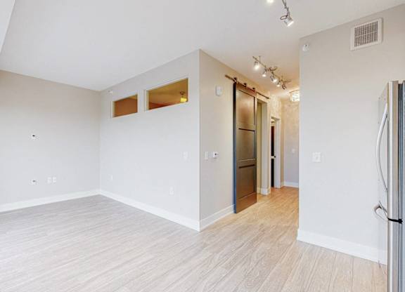 A spacious room with white walls and wooden flooring.