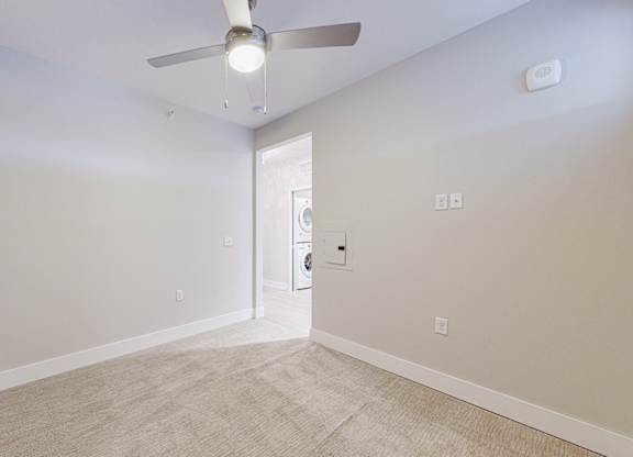 A room with a ceiling fan and carpeted floor.