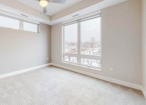 A room with a carpeted floor and a ceiling fan.