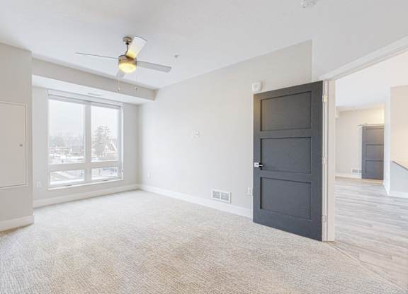 A room with a ceiling fan and a large window.