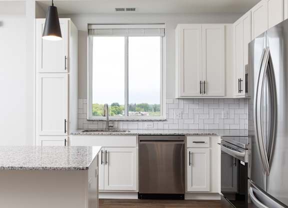A modern kitchen with white cabinets and stainless steel appliances.at The Edison at Maple Grove, Maple Grove