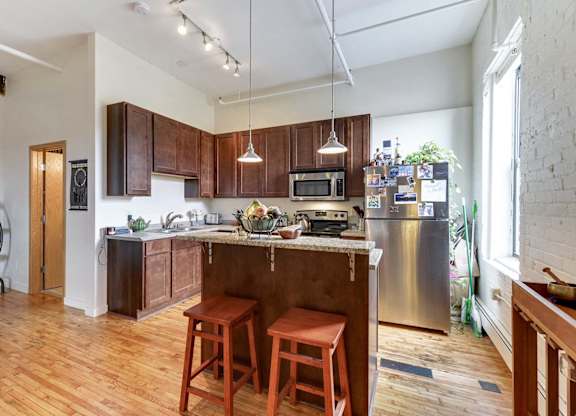 A kitchen with wooden floors and a large island with a bar stool.at Lee Lofts, Minneapolis, MN
