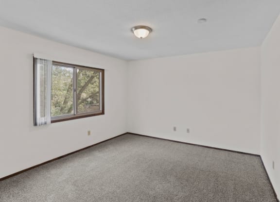 a bedroom with white walls and a large window