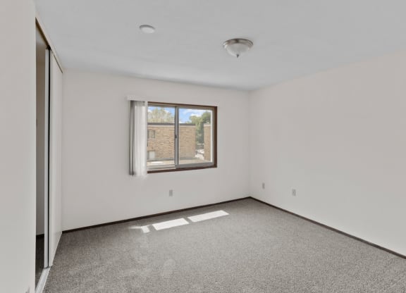 a bedroom with white walls and a large window