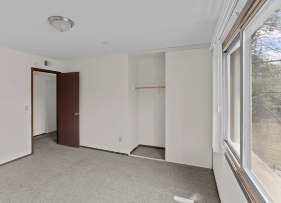 a bedroom with white walls and a large window
