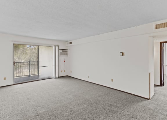 an empty living room with a sliding glass door and a balcony