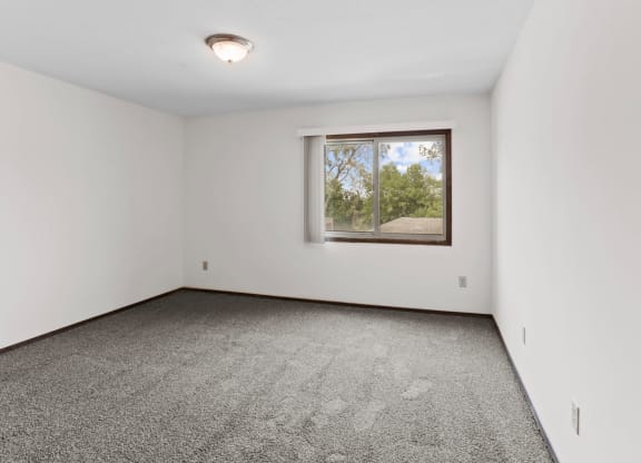 a bedroom with white walls and a large window