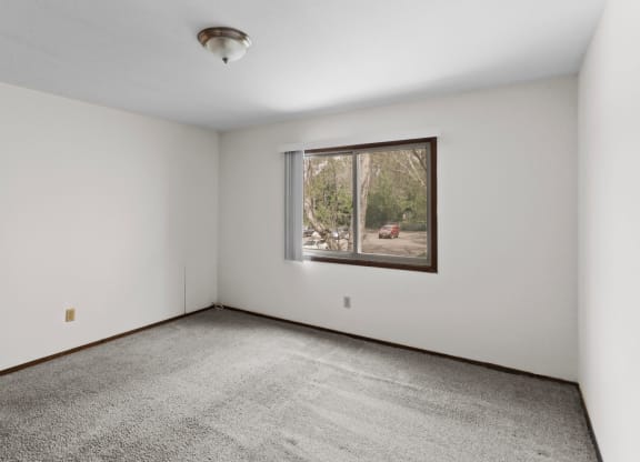 a bedroom with white walls and a large window