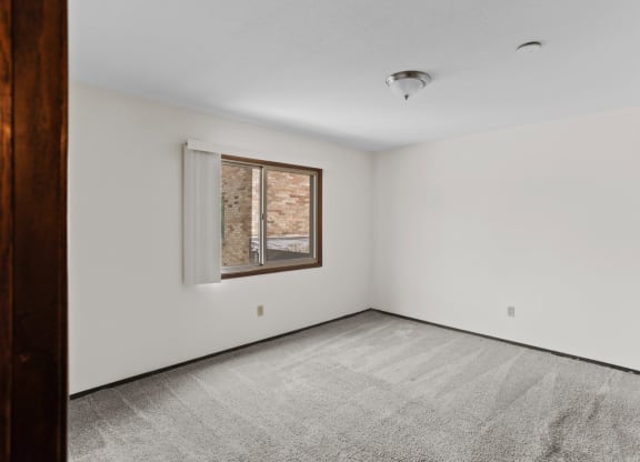 a bedroom with white walls and a window
