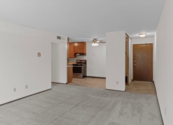 a bedroom with a ceiling fan and a kitchen in the background