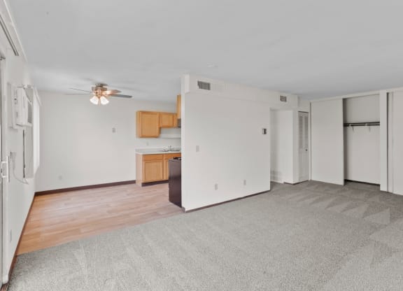 a living room with a ceiling fan and a kitchen in the background