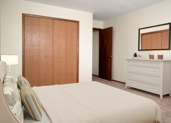 a bedroom with a bed and a dresser at Point of America Apartments, Brooklyn Park, MN