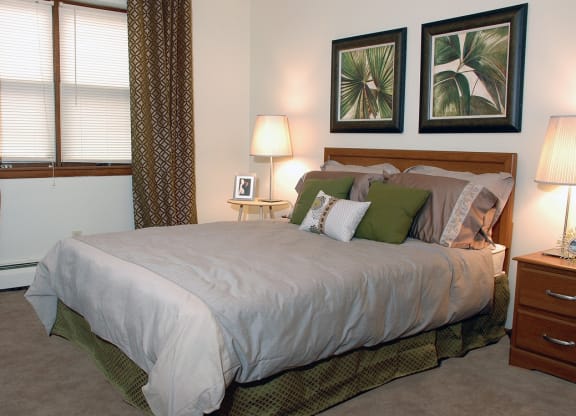 a bedroom with a bed and two night stands with lamps at Point of America Apartments,Brooklyn Park