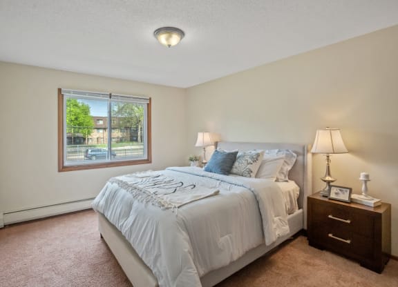 a bedroom with a large bed and a large window at Point of America Apartments,Brooklyn Park