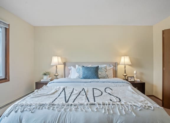 a bedroom with a bed and two nightstands at Point of America Apartments,Brooklyn Park