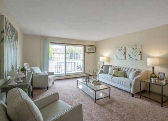 a living room with a large window and a sliding glass door at Point of America Apartments, Brooklyn Park, MN 55443