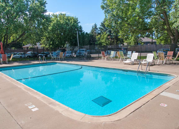 a swimming pool with chairs around it and trees