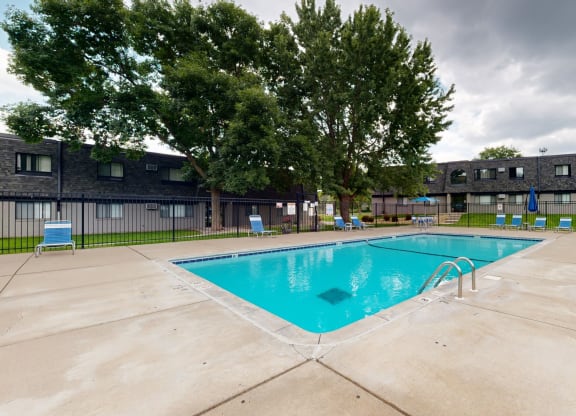 a swimming pool with chaise lounge chairs and umbrellas in front of a building