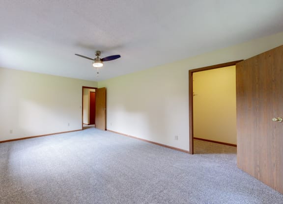 an empty living room with a ceiling fan