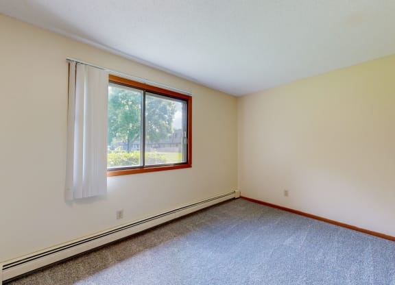 a bedroom with white walls and a window with a white curtain
