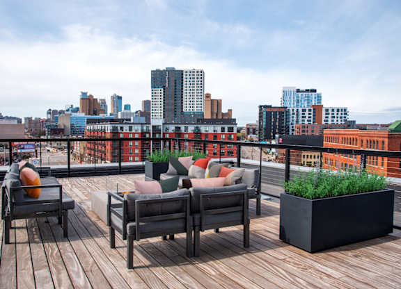 A wooden deck with two chairs and a table with a city skyline in the background.