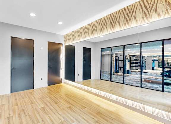 A room with wooden floors and a large window overlooking a city street.