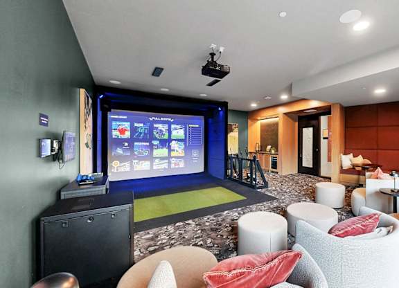 A modern living room with a large screen and comfortable seating.