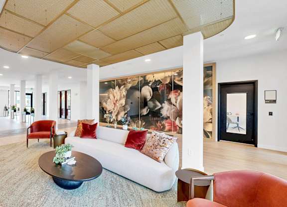 A living room with a white couch and a large painting on the wall.