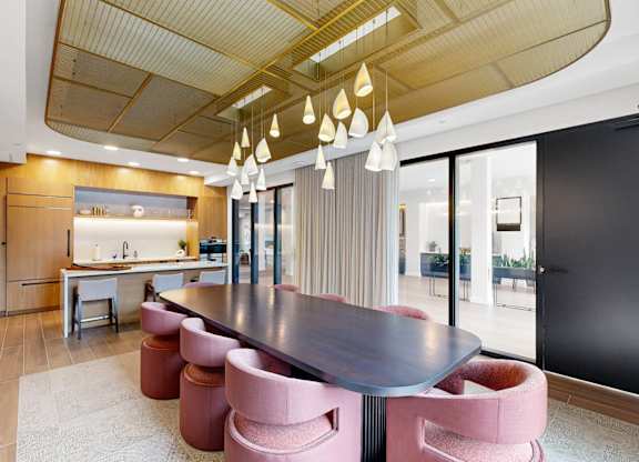 A modern dining room with a dark wood table and pink chairs.