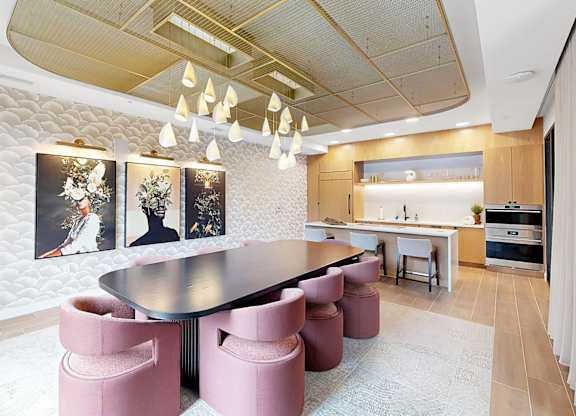 A conference room with a table surrounded by pink chairs.