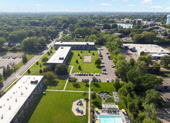 A large building complex with a green lawn and a pool in the foreground.