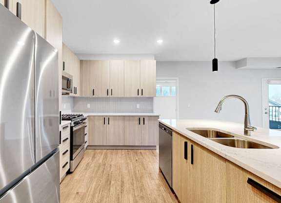 A modern kitchen with a stainless steel refrigerator and wooden cabinets.